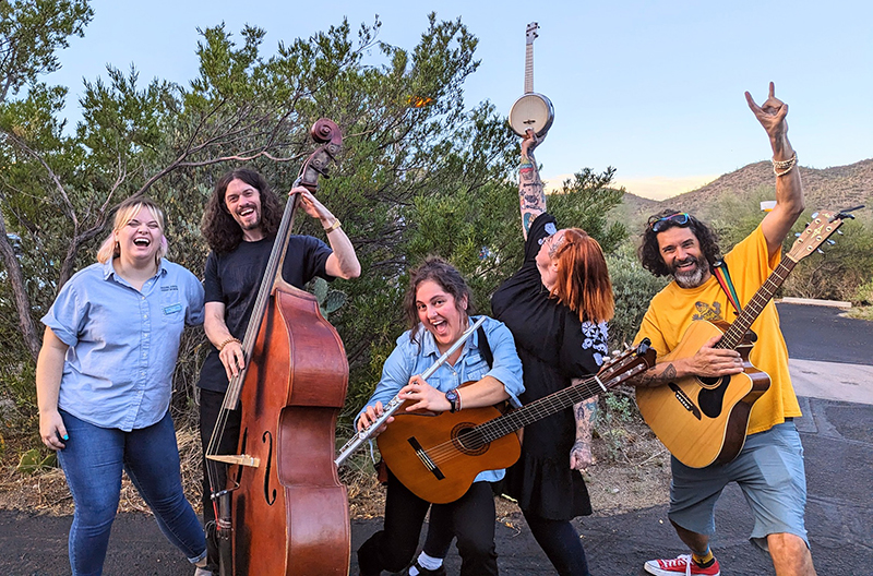 The Desert Museum Family Band smiling and posing with musical instruments. From left to right: Kyleigh, Eli, Michelle, Syndenn, and Mr. Nature